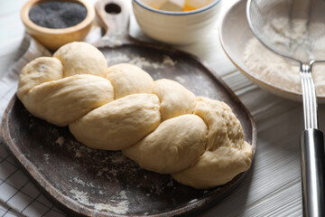 Homemade braided bread and ingredients on white wooden table, above view. Cooking traditional Shabbat challah