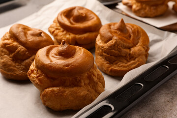 Freshly baked delicious profiteroles on grey table, closeup