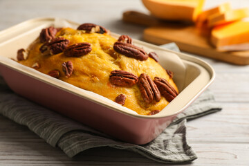 Delicious pumpkin bread with pecan nuts on light wooden table, closeup