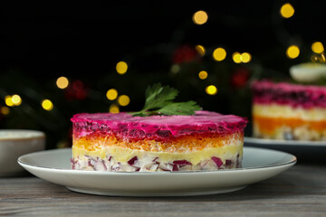 Herring under fur coat salad on white wooden table against blurred festive lights, space for text. Traditional Russian dish