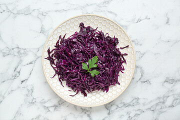 Tasty red cabbage sauerkraut with parsley on white marble table, top view