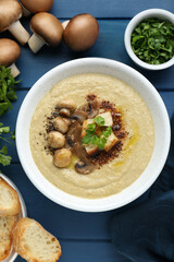 Delicious mushroom cream soup and ingredients on blue wooden table, flat lay