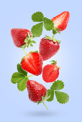 Delicious sweet strawberries and green leaves falling on pale light blue background