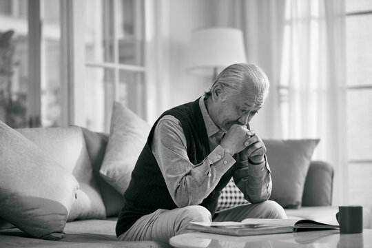 asian old man sitting alone on couch at home