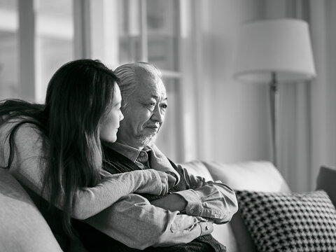 young asian daughter comforting elderly father black and white