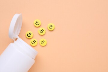 Bottle and yellow antidepressant pills with happy faces on pale orange background, flat lay. Space...