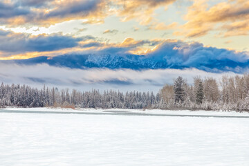 colorful scene along the Flathead River, Montana, of a sunrise with mountains in the background