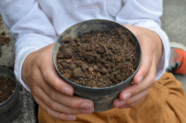 Hand of child holding a pot full of soil. Gardening.Planting seeds.