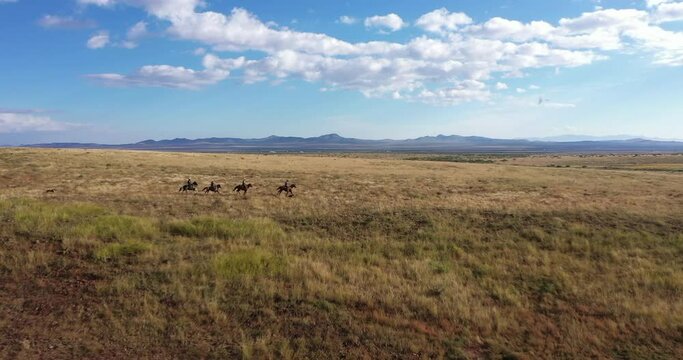 Aerial shot of horse riding cowboys on a hillside.