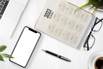 Madrid, Spain - February 03, 2023 Mockup: office table with pen, notebook, mobile phone with blank screen, glasses and Calendar