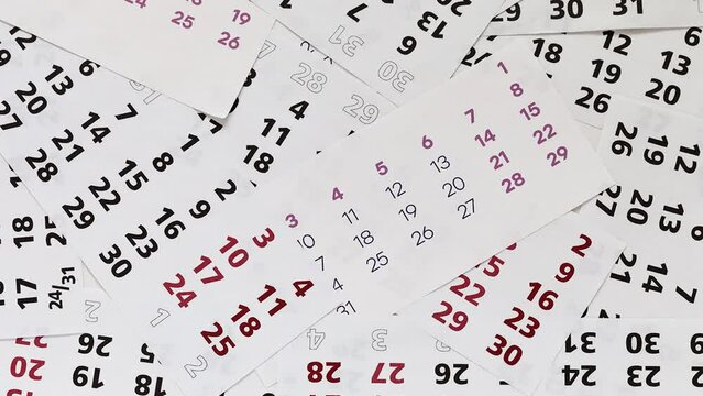Flat lay of calendar sheets of different months. Paper background of black and red numbers. The concept of time and events. Vacation planning, loan payments and taxes. Top view, close-up, mock up