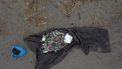 Aerial rises from tarp of trash during beach clean up event in Bali