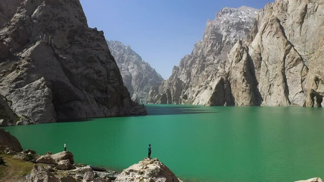 Revealing aerial shot going through a large ravine over the Kel-Suu lake in Kyrgyzstan, passing over a man overlooking the lake
