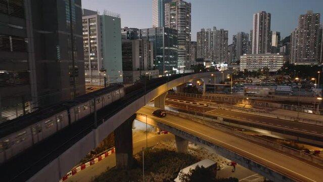 Follow shot of train passing overpass and traffic in Kwai Chung District of Hong Kong at blue hour