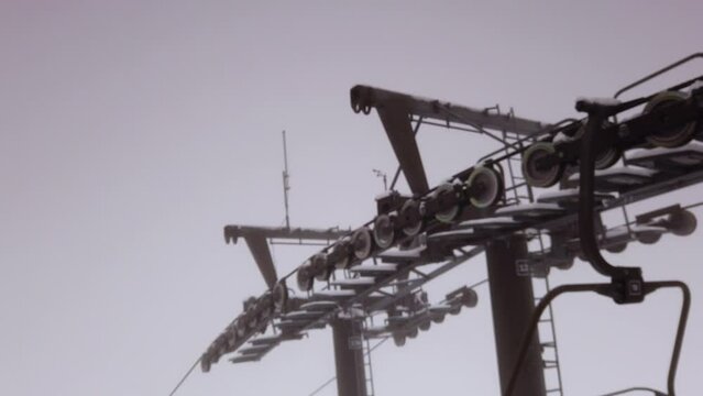 Mechanical steel ski resort chair lift pulley system rails down snowy winter mountain, Poland