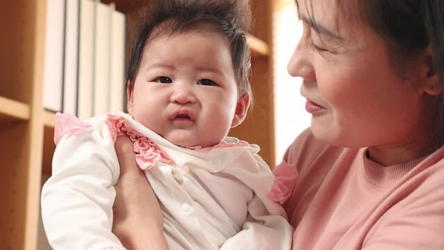 Asian beautiful mother holding adorable newborn baby with love and care, pov shot mom looking to infant nurturing embracing at home, Happy affectionate mother and toddler move around cuddling child gi