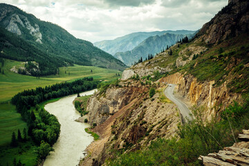 Curve road in the mountains. Chuisky tract with moving cars, Altai Republic, Siberia. A picturesque section of the federal highway along the Katun River.