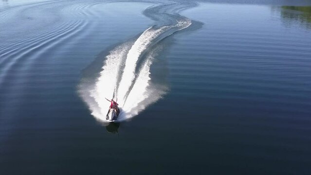 Aerial view of couple enjoying sporty jet ski ride on dark water lake