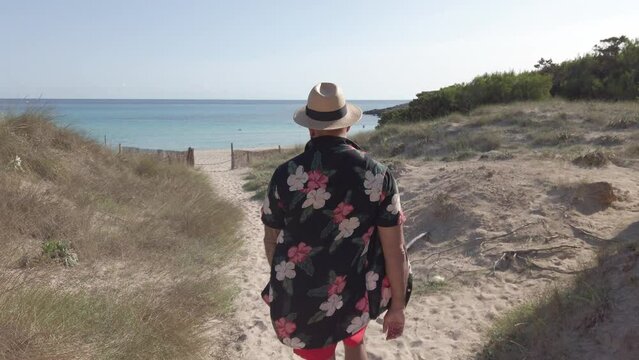 man walking through the dunes of cala agulla