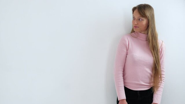 Angry young woman posing in front of the white wall. Medium slow motion shot