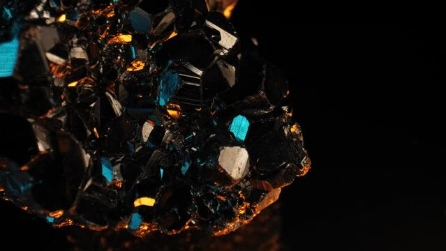 Luminous golden pyrite crystal gleaming against a rich, dark background. Silky smooth panning shot captured with a macro lens. Striking blue highlights.