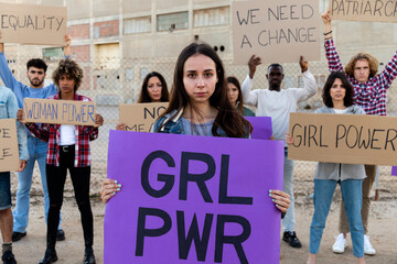 Young woman holding a girl power sign in demonstration for equality and woman's rights. Protesters...