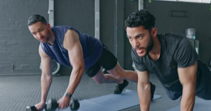 Gym, man and personal trainer planking with dumbbell together for arm fitness and stomach muscle training on floor. Exercise, health and body care, fit friends workout with kettlebell at sports club.