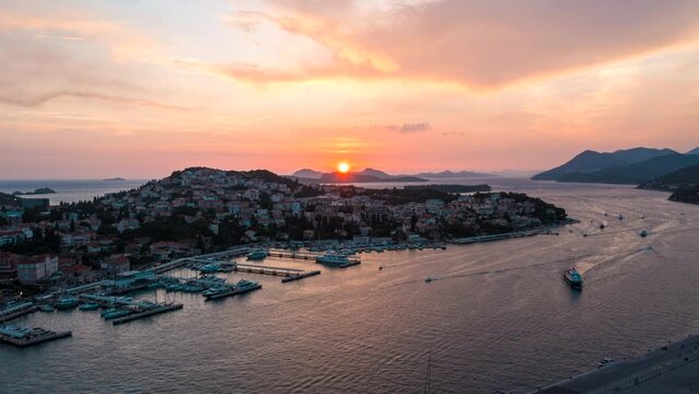 Aerial hyperlapse of the sun setting over an active coastal port in Dubrovnik, Croatia.