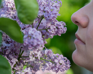 Caucasian woman sniffs a blooming lilac. Spring mood.