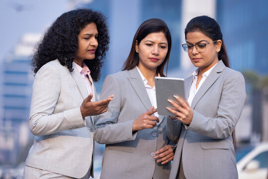 Businesswomen using digital tablet outside office building