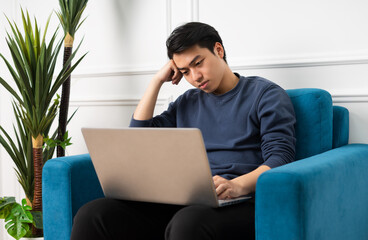 portrait of asian man sitting on sofa at home