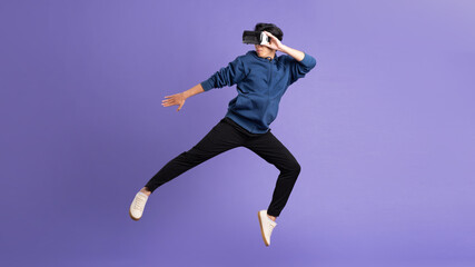 Fototapeta na wymiar image of asian man wearing virtual reality glasses on purple background