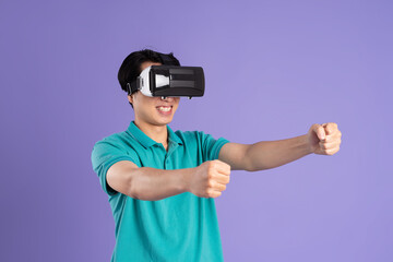 image of asian man wearing virtual reality glasses on purple background