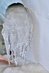 Frozen water at the outlet of the drainpipe close-up