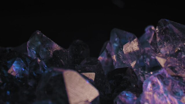 Smooth stunning pan of purple amethyst gem lit against a black background. Cinematic macro videography.