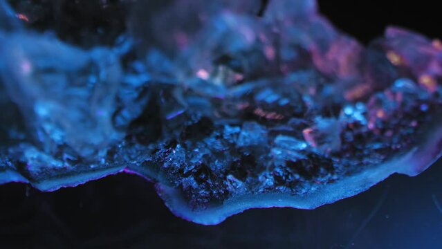 Luminous purple amethyst crystal against dark background. Smooth panning and purple studio lighting for exquisite details. Macro lens.