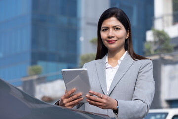 Happy businesswoman holding digital tablet outside office building