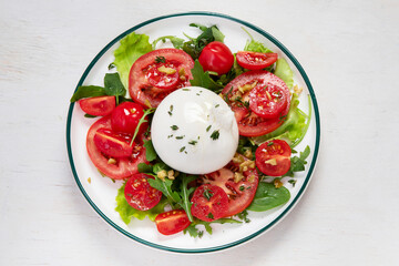 Delicious caprese salad with tomatoes and mozzarella cheese with fresh leaves. Italian food.