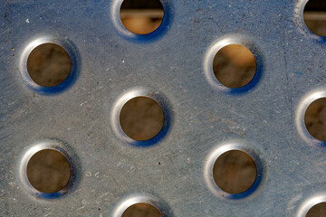 Close-up top view of iron sheet with round holes of ticket machine at bus station at City of Zürich district Schwamendingen on a sunny winter day. Photo taken January 31st, 2023, Zurich, Switzerland.