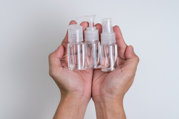 Hand holding three bottle of alcohol liquid hand sanitisers with isolated white background.