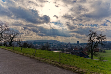 Skyline of City of Zürich on a cloudy winter noon with god rays seen from hill at district Seebach. Photo taken January 31st, 2023, Zurich, Switzerland.