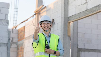 Professional engineer inspecting the construction of a house or factory building and giving a thumbs up showing readiness and good performance, Engineer's safety suit and helmet.
