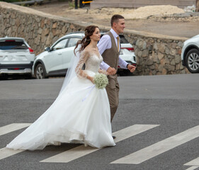Fototapeta premium The bride and groom in a wedding dress on a pedestrian crossing.