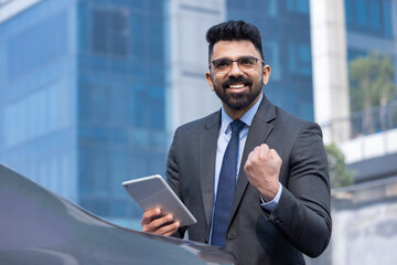 Portrait of Indian businessman with digital tablet outdoors in city.