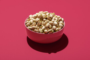 Pistachio in a pink bowl, minimalist on a magenta background