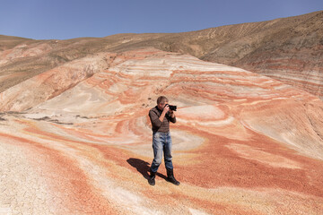 Photographer in the red mountains. Khyzy region. Azerbaijan.