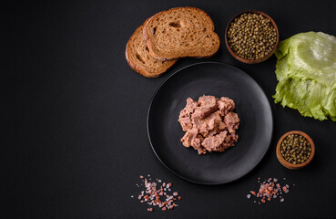 Delicious canned tuna meat on a black ceramic plate on a dark concrete background