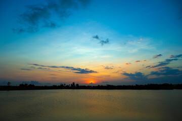 beautiful teal and orange color sunset at the lake on agricultural land in the village