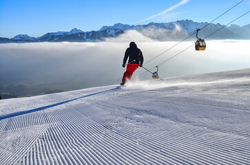 Skifahren, Skiläufer auf Piste mit Panorama auf Winterlandschaft, Berge, Nebel im Tal, Schnee und Gondel