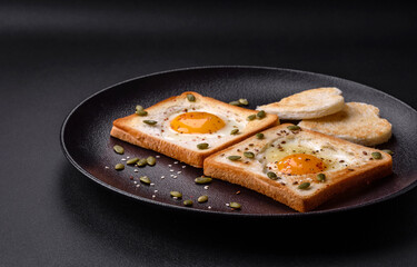 Heart shaped fried egg in bread toast with sesame seeds, flax seeds and pumpkin seeds on a black plate